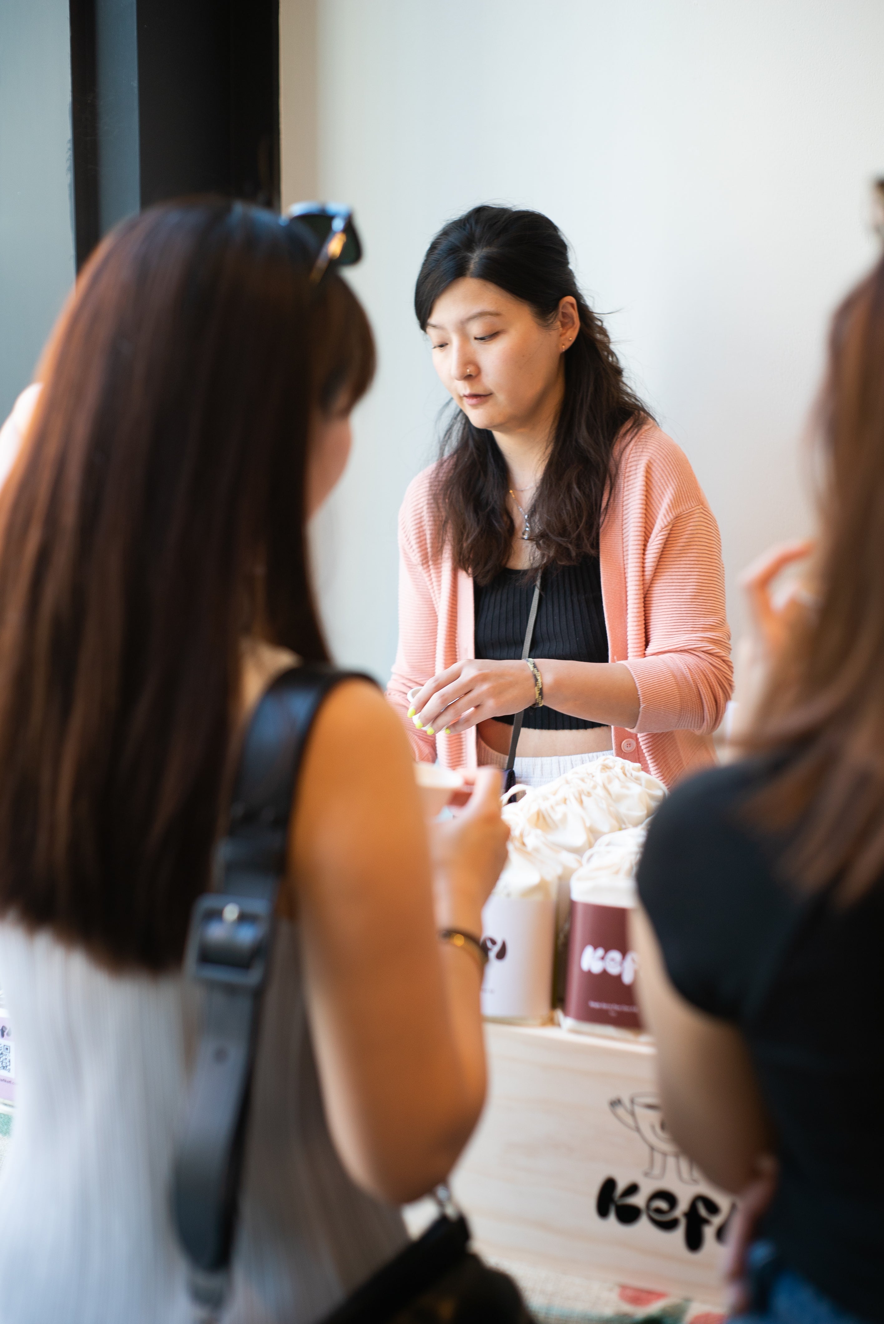 Angela Kefi Founder in a pink sweater interacting with two other women in a casual Mogutable pop up.